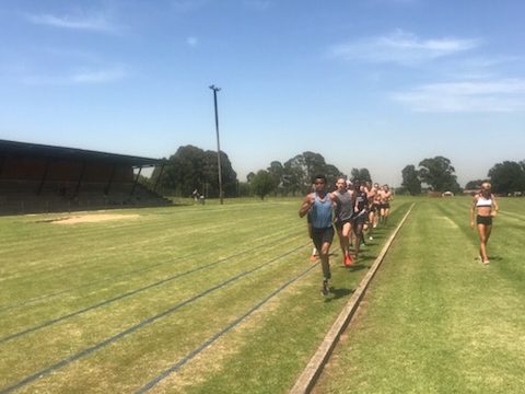 landslagslöpare tränar i grupp på läger tillsammans med naprapat från rygg och led